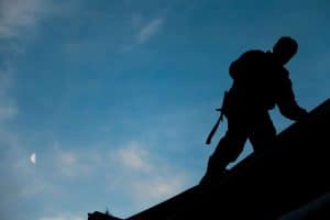 A man climbing on to his roof
