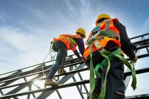 Two roof plumbers wearing appropriate safety equipment on the roof